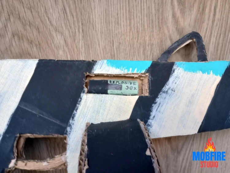 Explosive shell inserted into custom cutout in cardboard AA-12 build